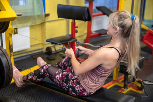 Gym equipped with professional sports equipment. A woman exercises at the gym. A young person keeps fit by coming to the gym and exercising on professional equipment.