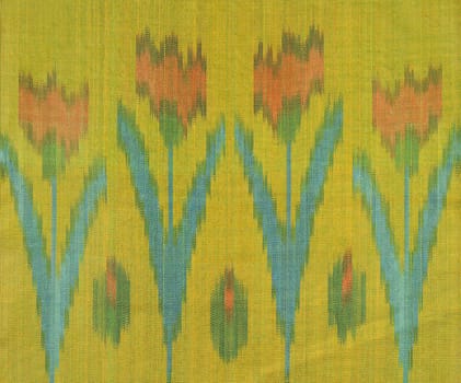 A design of red tulip flowers with green leaves on a yellow fabric