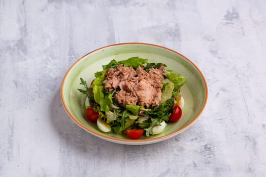 A closeup of tuna salad in a bowl isolated on a white wooden background