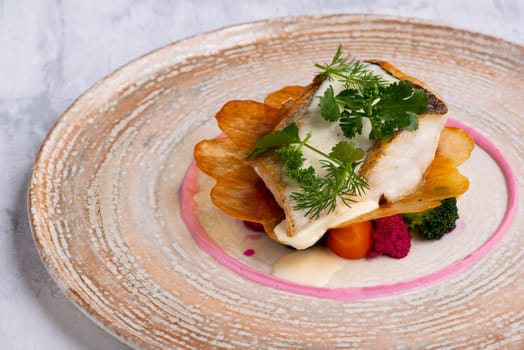 A closeup of pike perch with vegetables on plate