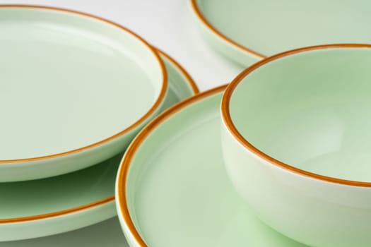 A set of pastel green ceramic tableware with orange outlines