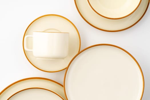 A set of white and brown ceramic plate and cup on a white background. Top view