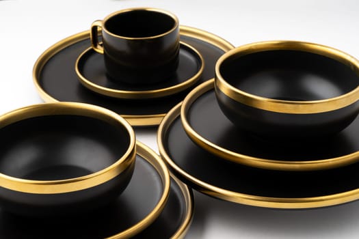 A set of black and golden ceramic plates and cup on a white background