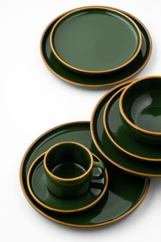 A set of dark green ceramic tableware with orange outlines on a white background