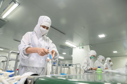 The workers in the workshop for the production of medical syringes and droppers