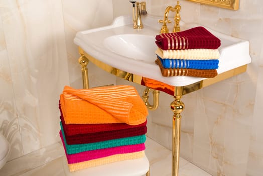 The folded colorful bamboo towels in a beautiful vintage golden bathroom interior