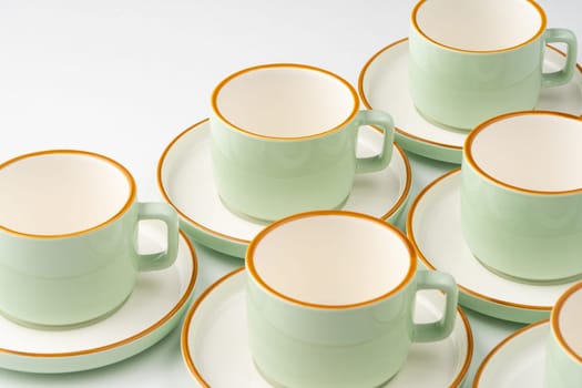 A set of white and pastel green ceramic teacups with orange outlines