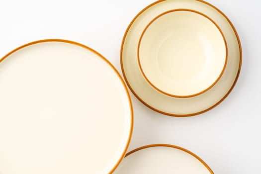 A set of white and brown ceramic plate and bowl on a white background. Top view