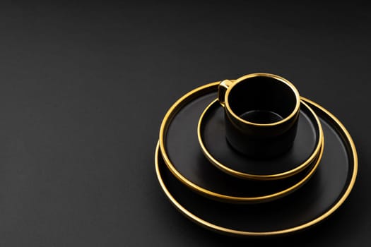 A set of black and golden ceramic plates and cup on a black background