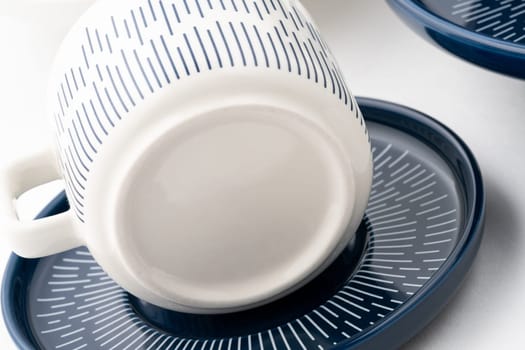 A closeup shot of a blue and white mug on a saucer with a white background