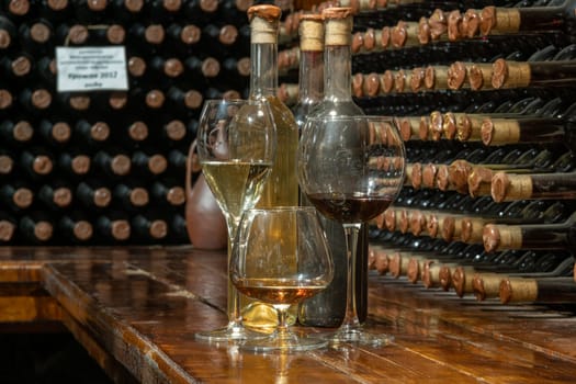 A closeup of bottles of different types of wine with a wine cellar in the background. Wine tasting