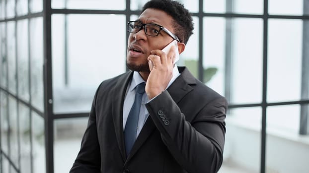 Portrait of an African American businessman standing outside the office and talking on the phone