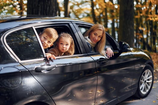 In the car. Happy family is in the park at autumn time together.