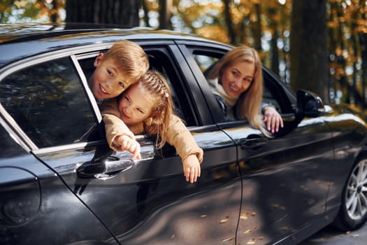 In the car. Happy family is in the park at autumn time together.