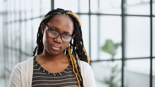 young woman in glasses standing looking at camera in modern office