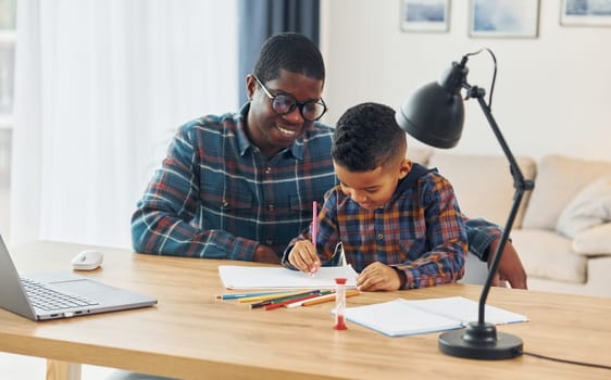 Drawing lessons. African american father with his young son at home.