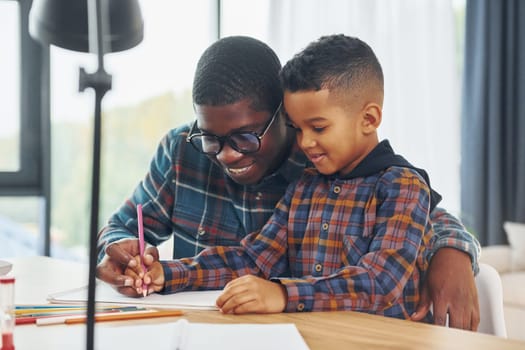 Drawing lessons. African american father with his young son at home.