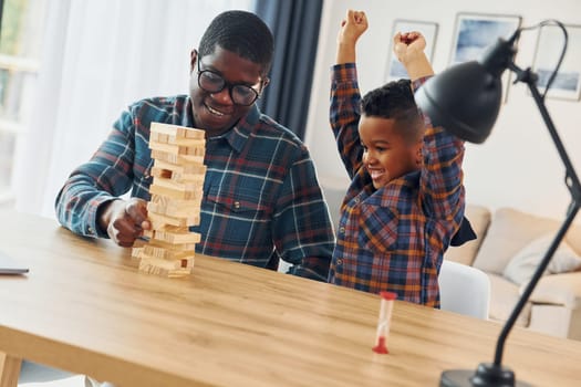 Playing bricks game. African american father with his young son at home.