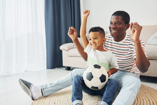 With soccer ball. African american father with his young son at home.