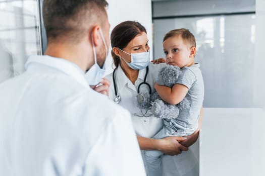 With little boy that being examined. Two doctors in white coats is in the clinic working together.