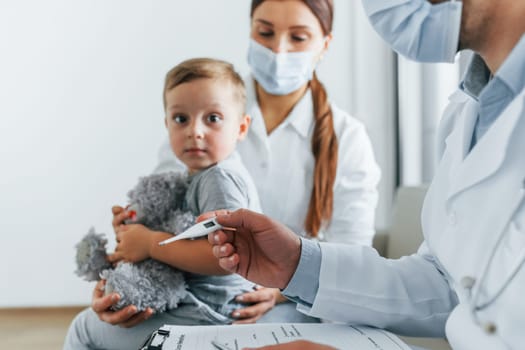 With little boy that being examined. Two doctors in white coats is in the clinic working together.