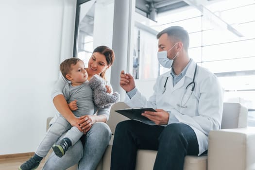 The little boy is being examined. Two doctors in white coats is in the clinic working together.