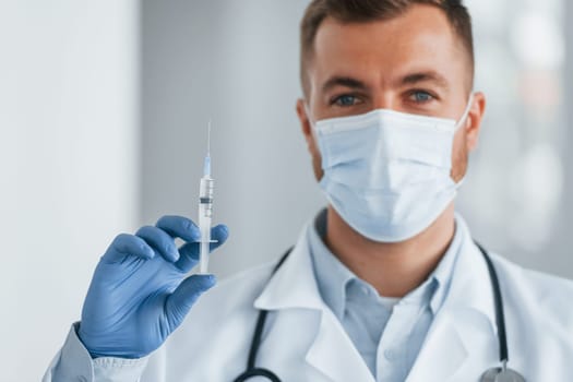 Posing for the camera. Professional medic in white coat is in the clinic.