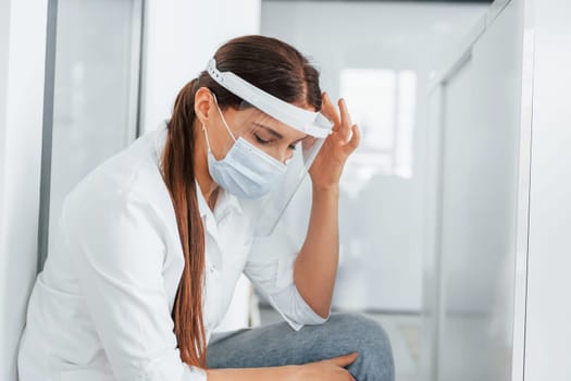 Having headache. Professional medic in white coat is in the clinic.