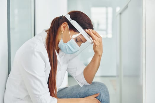 Having headache. Professional medic in white coat is in the clinic.