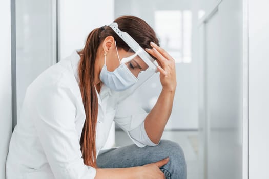 Having headache. Professional medic in white coat is in the clinic.