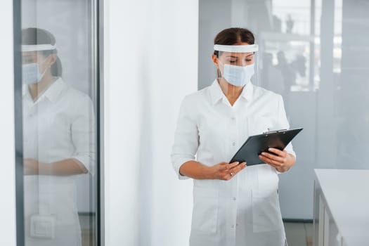 Notepad in hands. Professional medic in white coat is in the clinic.