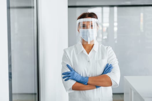 Standing indoors. Professional medic in white coat is in the clinic.