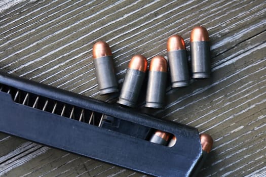 Handgun cartridges closeup on old wooden background