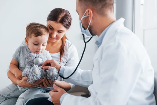 Helping the child. Two doctors in white coats is in the clinic working together.