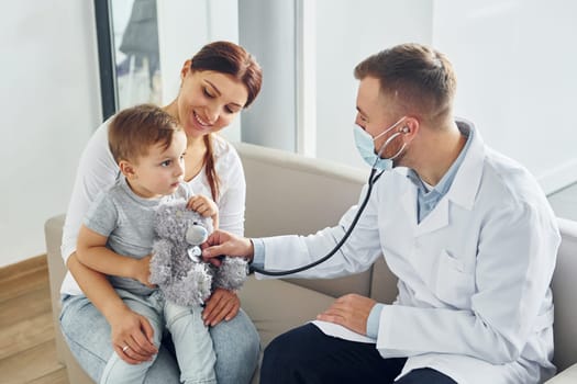 Helping the child. Two doctors in white coats is in the clinic working together.