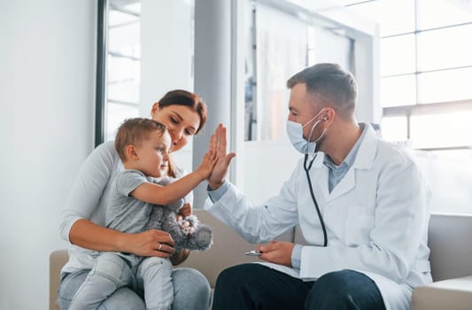 Helping the child. Two doctors in white coats is in the clinic working together.