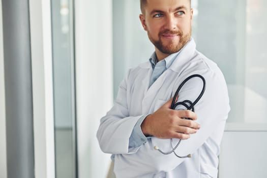 Stethoscope in hands. Professional medic in white coat is in the clinic.