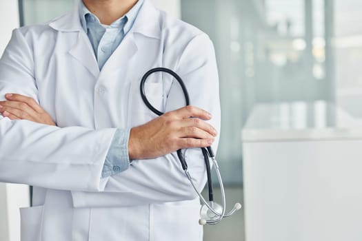 Holding stethoscope. Professional medic in white coat is in the clinic.