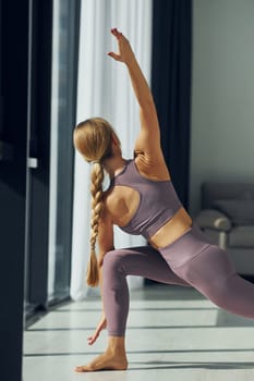 Focused on exercises. Woman in sportive clothes doing yoga indoors.