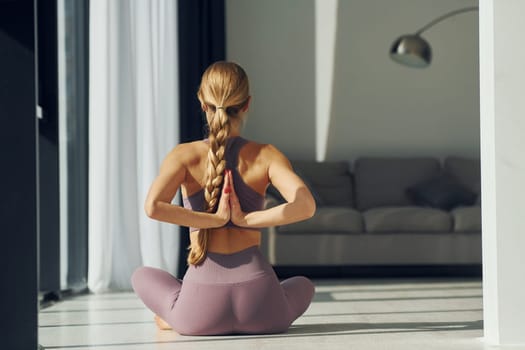 Posing for the camera. Woman in sportive clothes doing yoga indoors.