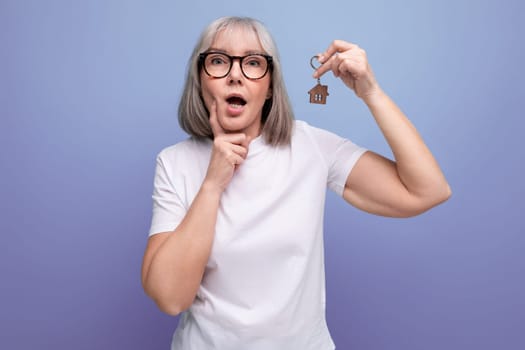 turnkey property. mature woman pensioner holding apartment keychain.