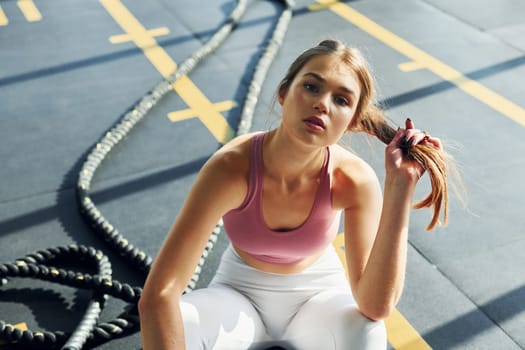 Sitting on the ground. Beautiful young woman with slim body type is in the gym.