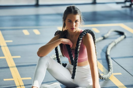 Resting on the ground. Beautiful young woman with slim body type is in the gym.