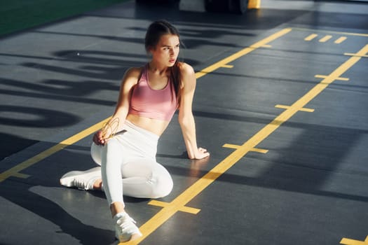 On the ground. Beautiful young woman with slim body type is in the gym.