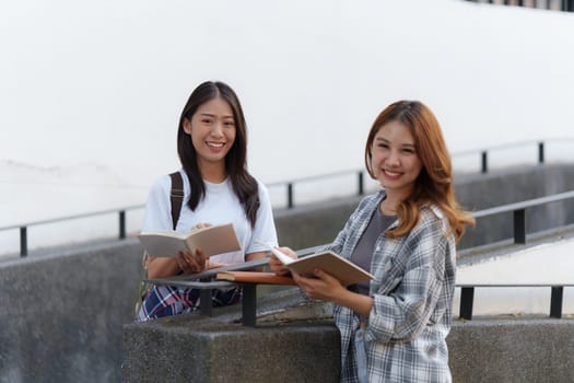 Young Asian woman college student with friends at outdoors. College student working on the college campus, education, school, study.