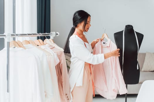 Conception of fashion. Seamstress is in her office that is with different clothes.