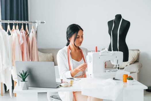 Professional sewing machine. Seamstress is in her office that is with different clothes.