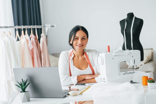 Professional sewing machine. Seamstress is in her office that is with different clothes.