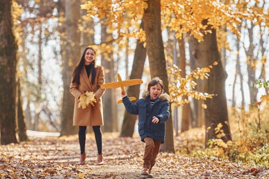 Playing with leaves. Mother with her son is having fun outdoors in the autumn forest.