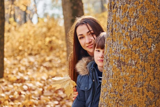 Cheerful woman and boy. Mother with her son is having fun outdoors in the autumn forest.